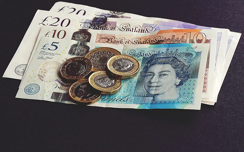 British currency notes and coins placed together.