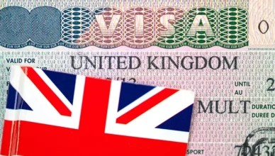 Close-up of UK visa in passport with British flag in background