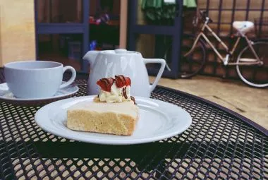 Cake on Ceramic Plate Near Teapot and Cups